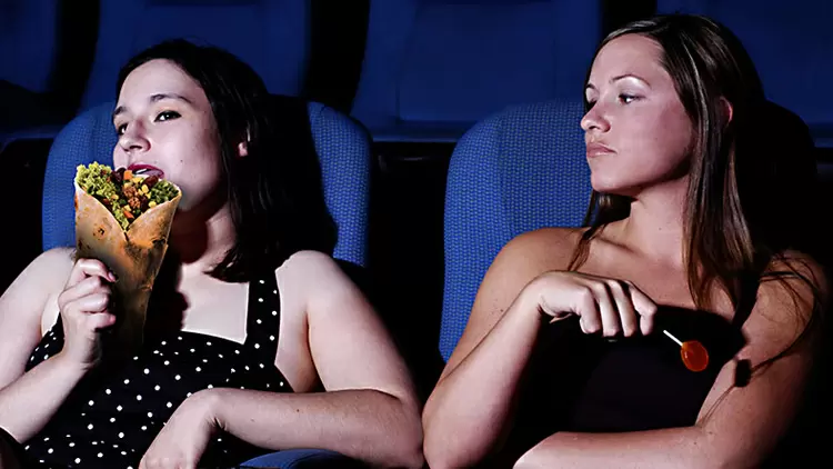 In a movie theater, if someone next to you is eating food with a strong smell, what would you do?